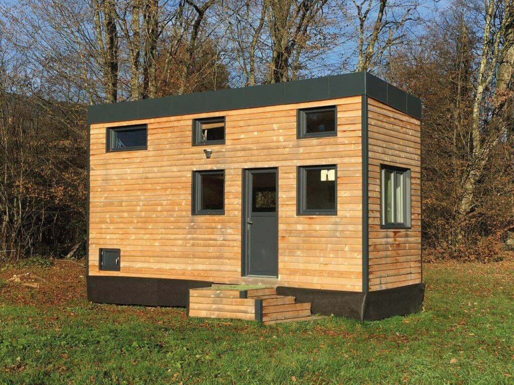 Tiny house en bois vue de l'extérieur dans un champ