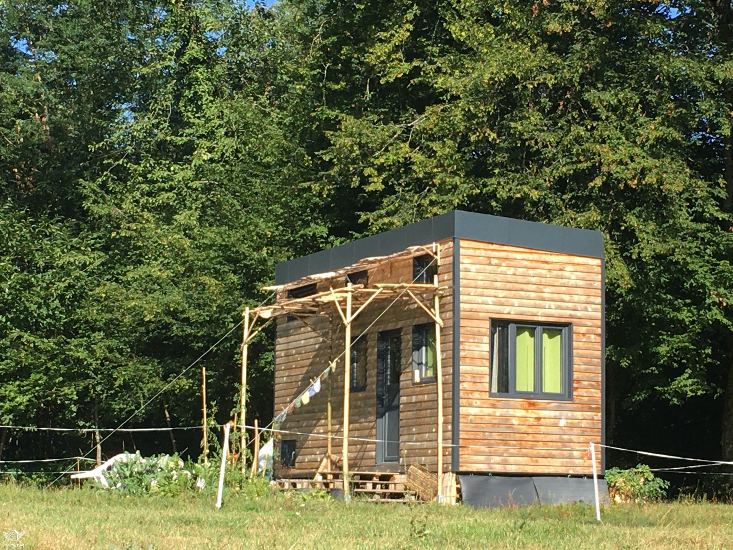 Tiny house en bois vue de l'extérieur dans un champ